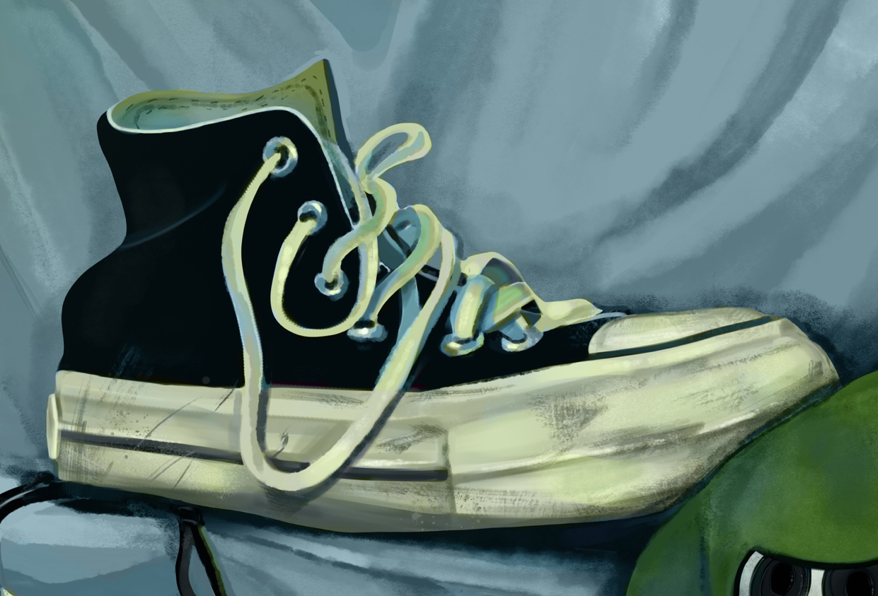 A close up view of the black converse, showing the scuff marks and the laces.